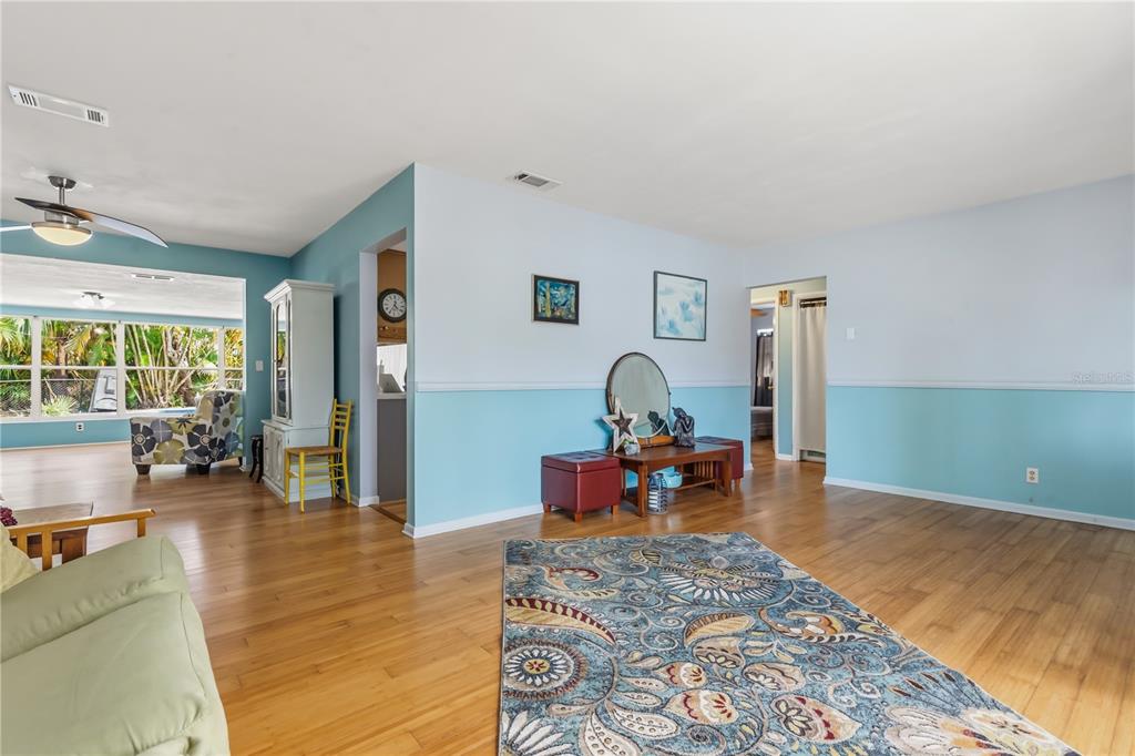 A living room features light blue walls, wood flooring, and a large patterned area rug — 1508 ERIN LANE, CLEARWATER, FL