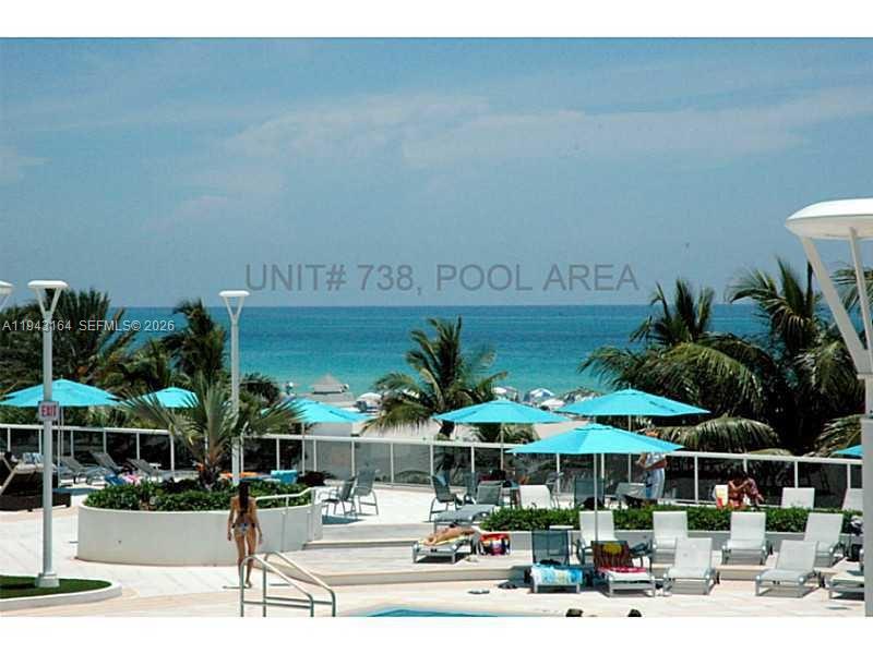 A swimming pool area overlooks the ocean with lounge chairs and umbrellas on a deck — 100 Lincoln Rd # 1440, Miami Beach FL 33139, MIAMI BEACH, FL
