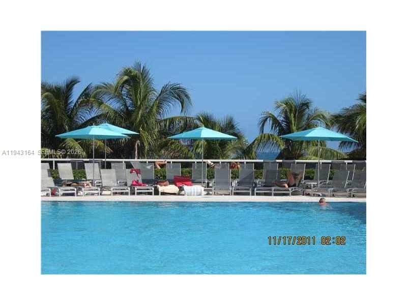 A swimming pool with lounge chairs and umbrellas sits in front of palm trees — 100 Lincoln Rd # 1440, Miami Beach FL 33139, MIAMI BEACH, FL