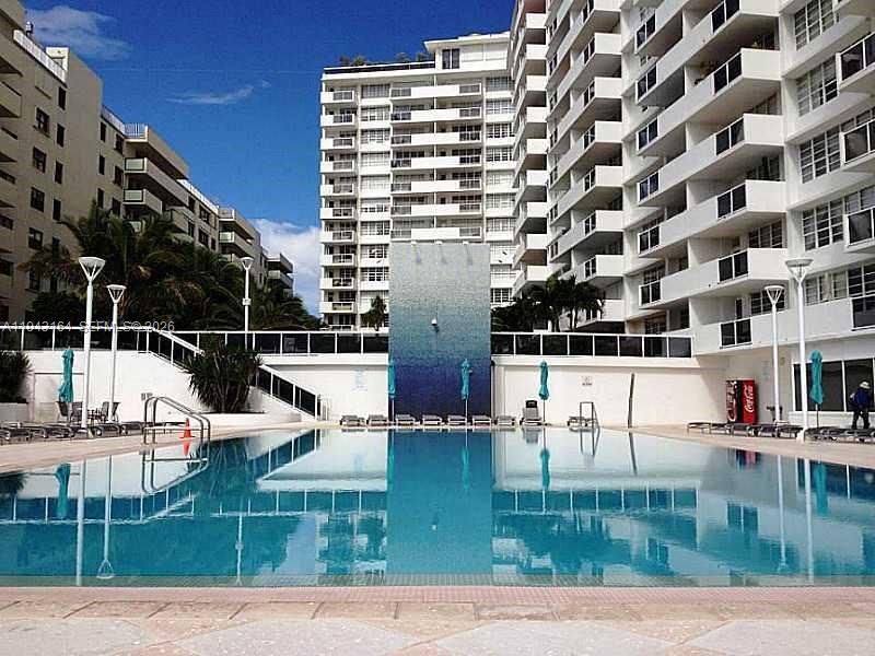 A swimming pool sits in front of a large, multi-story white apartment building — 100 Lincoln Rd # 1440, Miami Beach FL 33139, MIAMI BEACH, FL