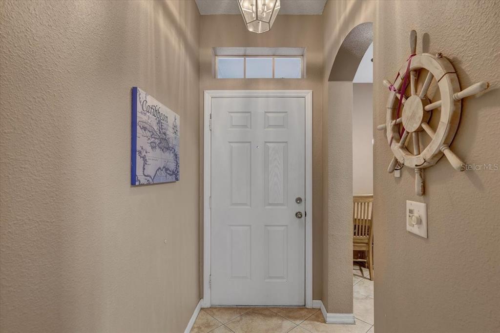 An entryway features a white front door, a nautical ship wheel, and a Caribbean map — 11208 WINDSOR PLACE CIRCLE, TAMPA, FL