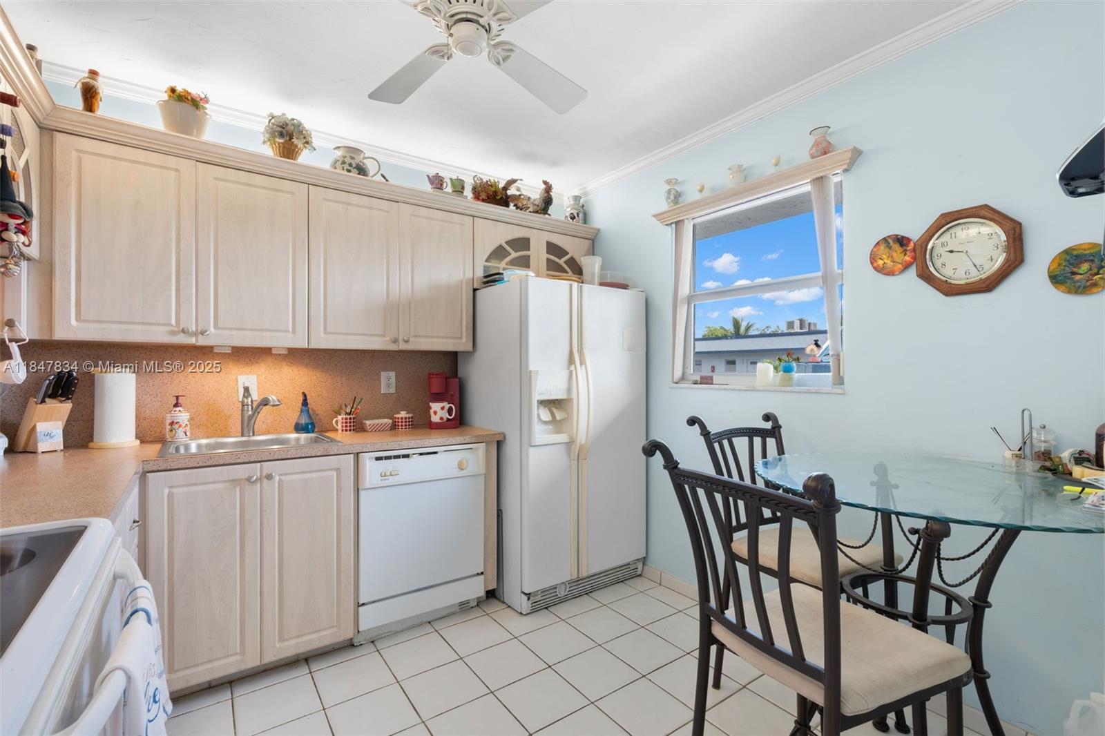A kitchen features light wood cabinets, white appliances, a glass-topped dining table, and tiled floors — 3120 Holiday Springs Blvd # 301, Margate FL 33063, MARGATE, FL