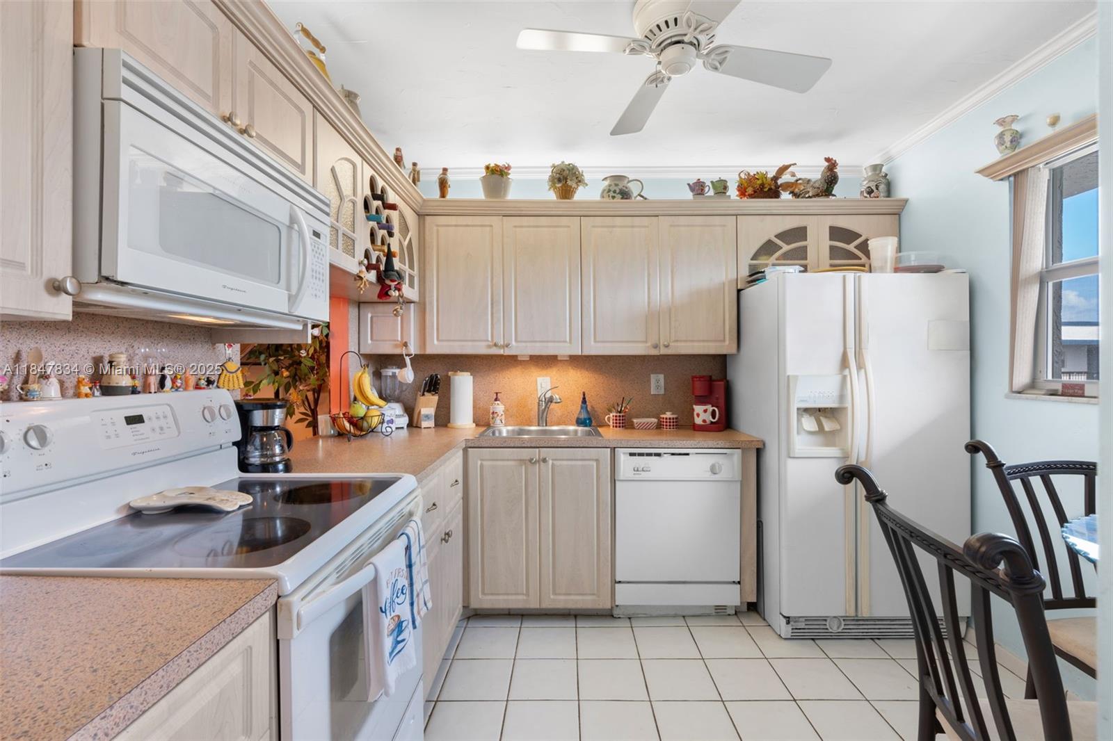 A kitchen with light wood cabinets, white appliances, a ceiling fan, and tiled flooring — 3120 Holiday Springs Blvd # 301, Margate FL 33063, MARGATE, FL