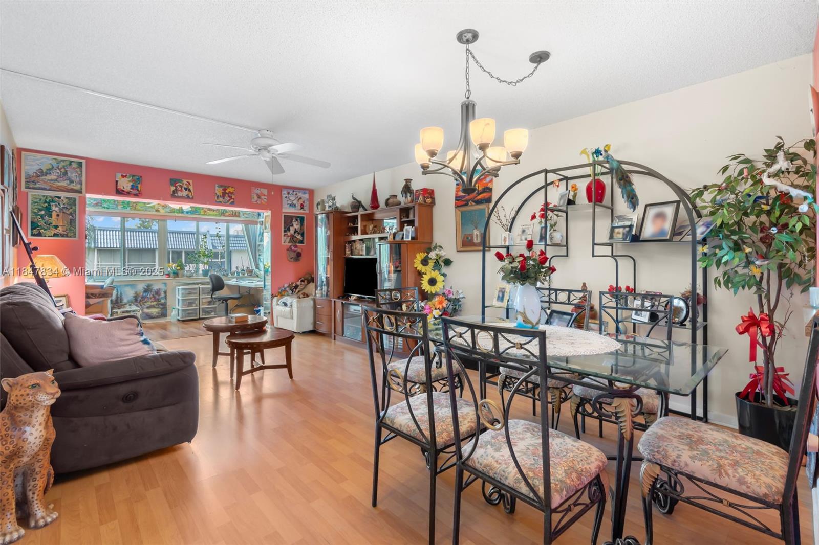 A living and dining area features wood-look flooring, a glass dining table, and pink walls — 3120 Holiday Springs Blvd # 301, Margate FL 33063, MARGATE, FL
