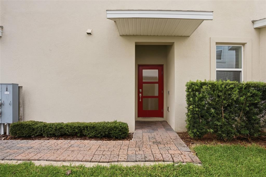 A red front door with three glass panels is centered on a beige exterior wall — 787 OCEAN COURSE AVENUE, KISSIMMEE, FL