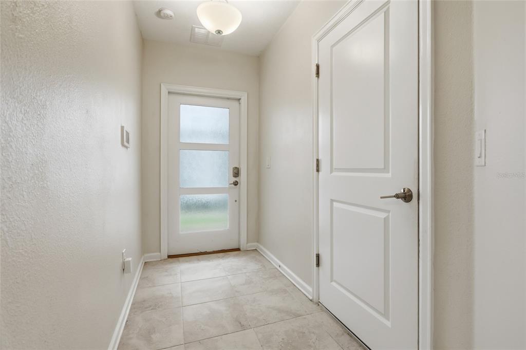An entryway features light-colored tile flooring, a frosted glass front door, and a white door — 787 OCEAN COURSE AVENUE, KISSIMMEE, FL