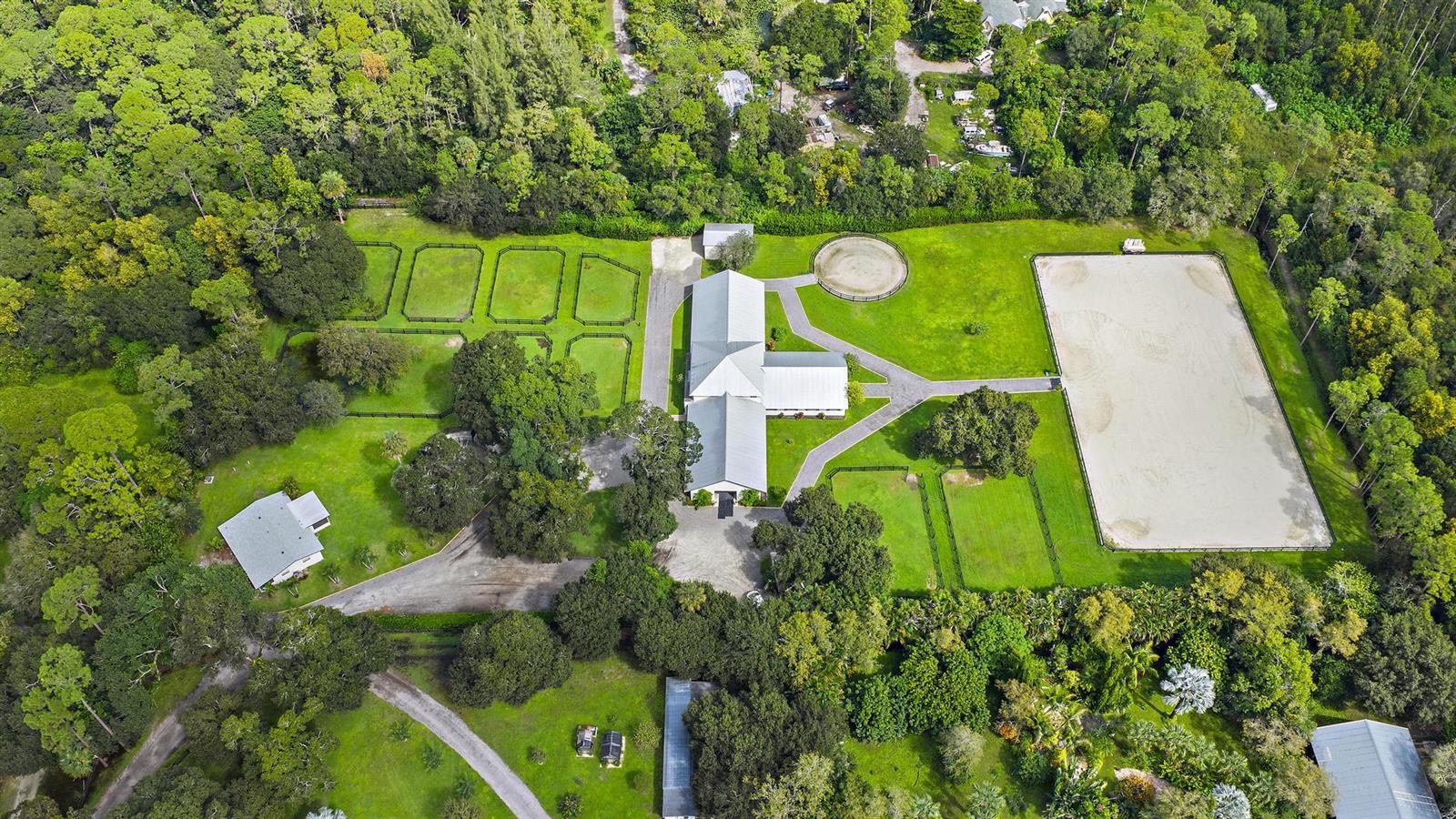 An aerial view shows a horse property with a barn, riding arena, and fenced paddocks — 14339 Collecting Canal Road, FL 33470, FL