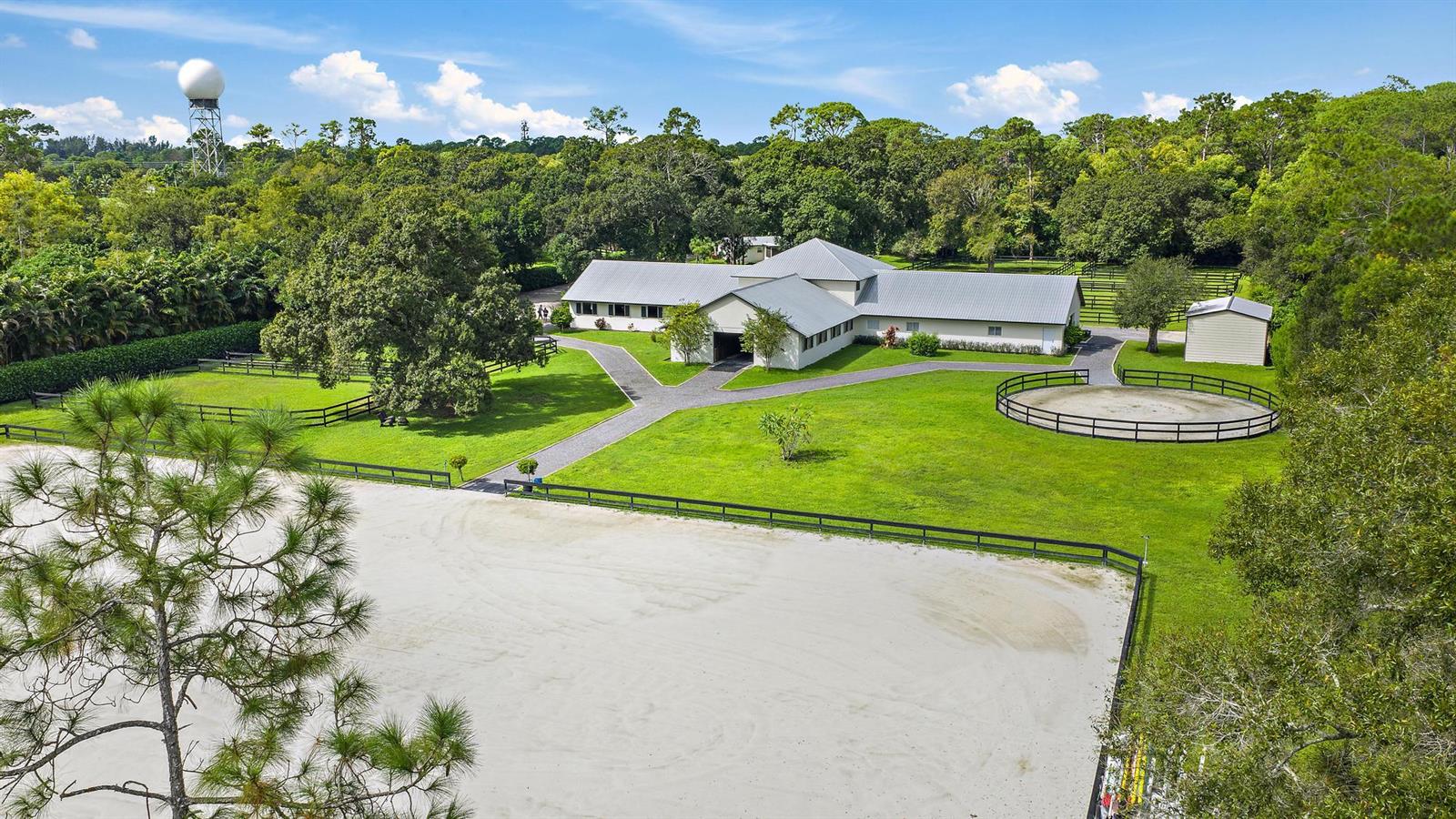 An aerial view shows a horse stable with a round pen and riding arena — 14339 Collecting Canal Road, FL 33470, FL