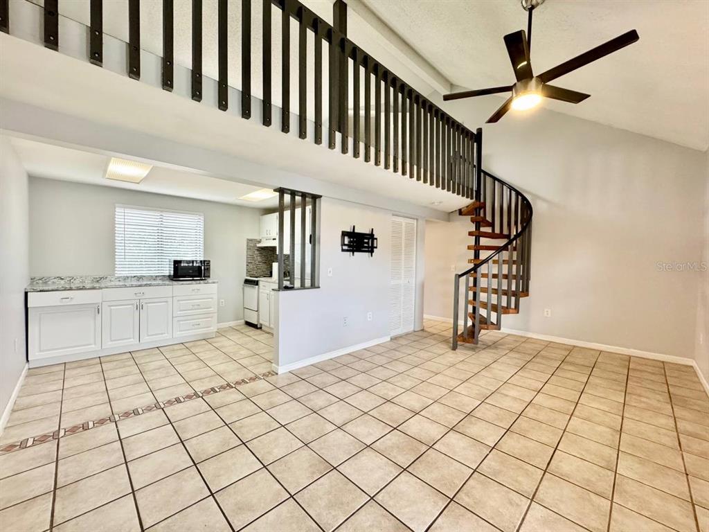 A kitchen and living area with tile floors, a spiral staircase, and a loft railing — 2166 BRADFORD STREET UNIT 125, CLEARWATER, FL