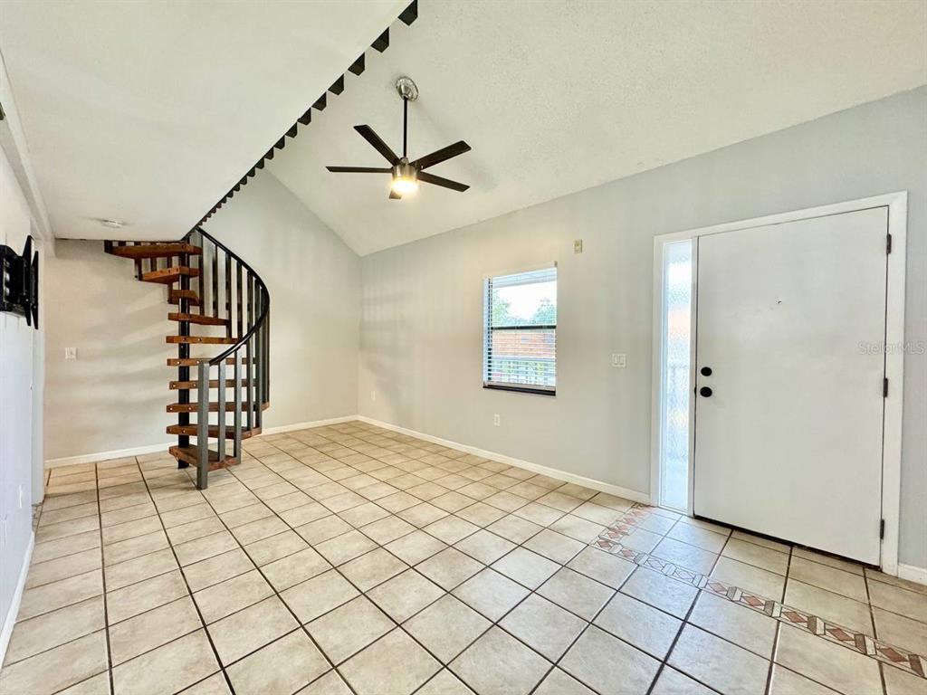 An empty room features tile flooring, a spiral staircase, and a vaulted ceiling with a fan — 2166 BRADFORD STREET UNIT 125, CLEARWATER, FL