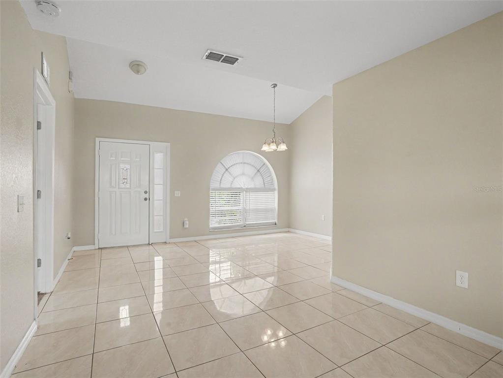 A bright room with beige tile flooring, a vaulted ceiling, and an arched window — 1802 HUDSON COURT, KISSIMMEE, FL