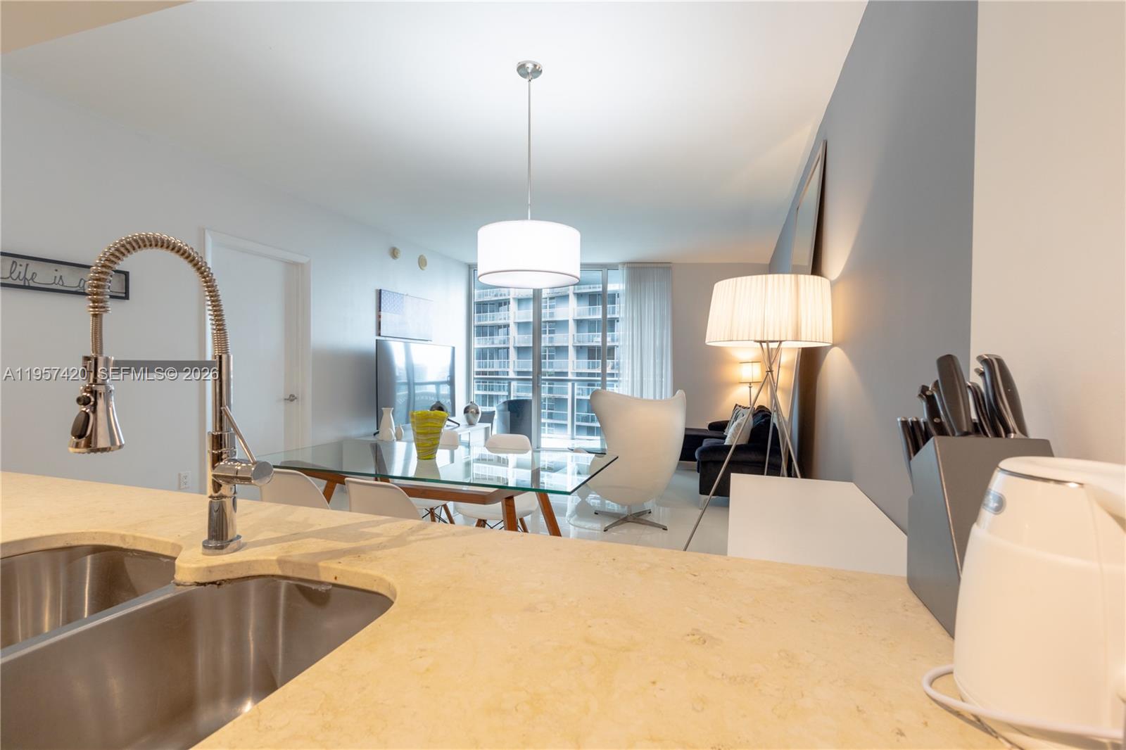 A kitchen counter overlooks a dining area and living room with a modern white chair — 475 Brickell Ave # 4511, Miami FL 33131, MIAMI, FL