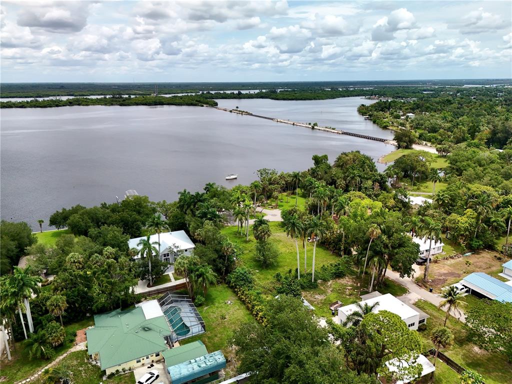 An aerial view shows houses nestled among trees along a large body of water — 304 ROYAL PALM PARK ROAD, FORT MYERS, FL