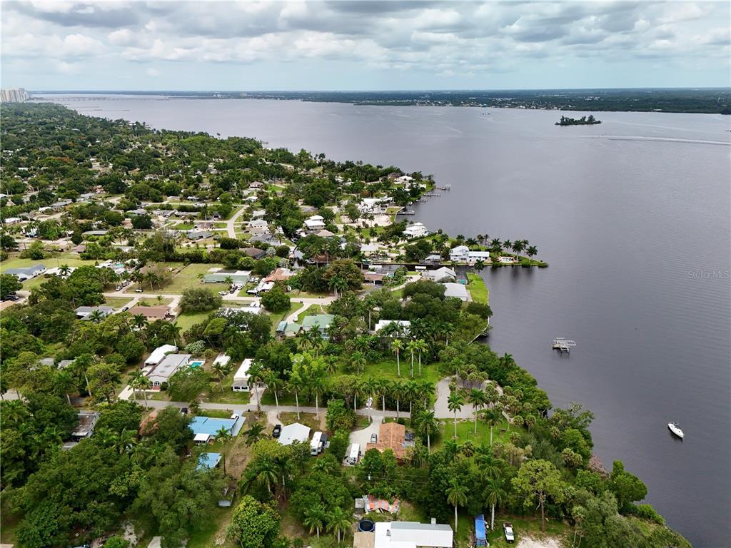 An aerial view shows a residential neighborhood situated along a large body of water — 304 ROYAL PALM PARK ROAD, FORT MYERS, FL