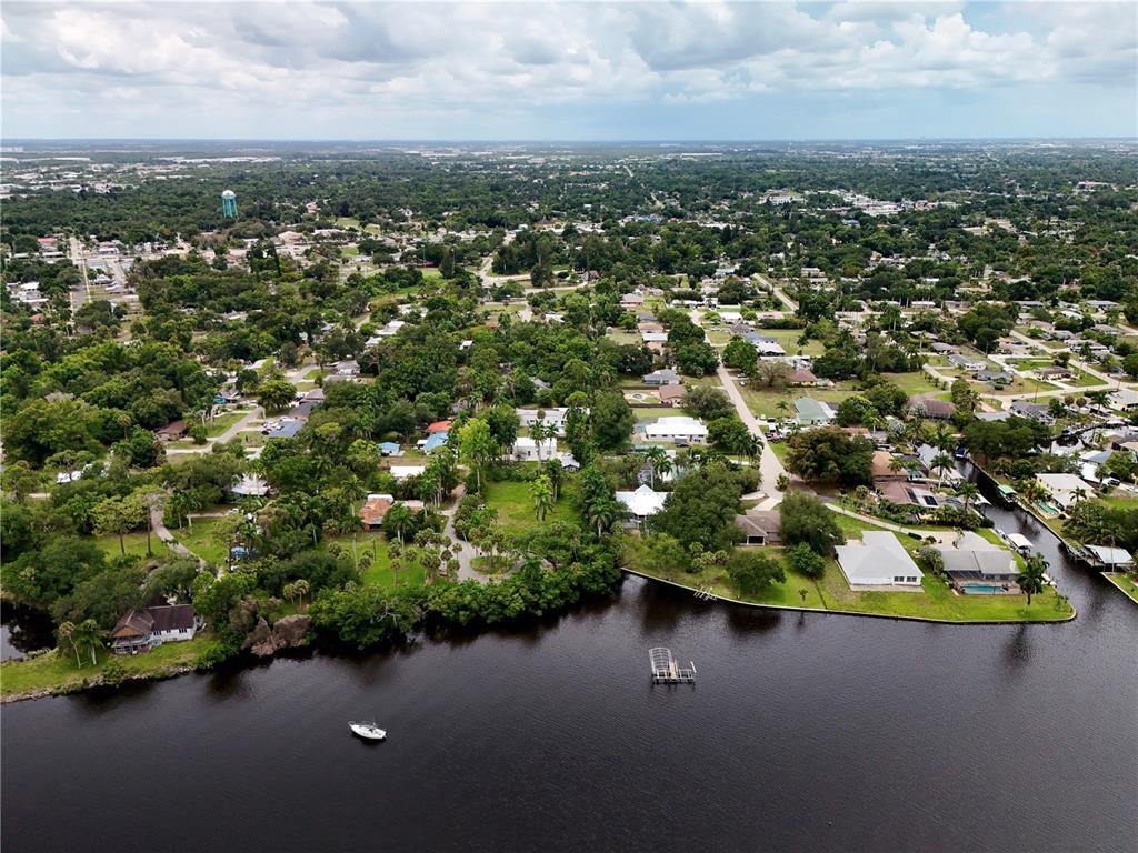 An aerial view shows a waterfront residential neighborhood with a dock and a small boat — 304 ROYAL PALM PARK ROAD, FORT MYERS, FL