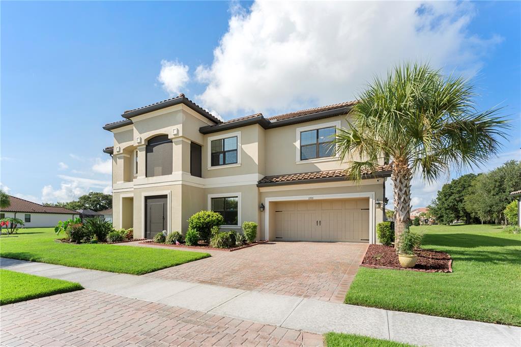 A two-story suburban house with a beige stucco exterior, a tile roof, and a brick driveway — 1100 WINDLASS COURT, KISSIMMEE, FL