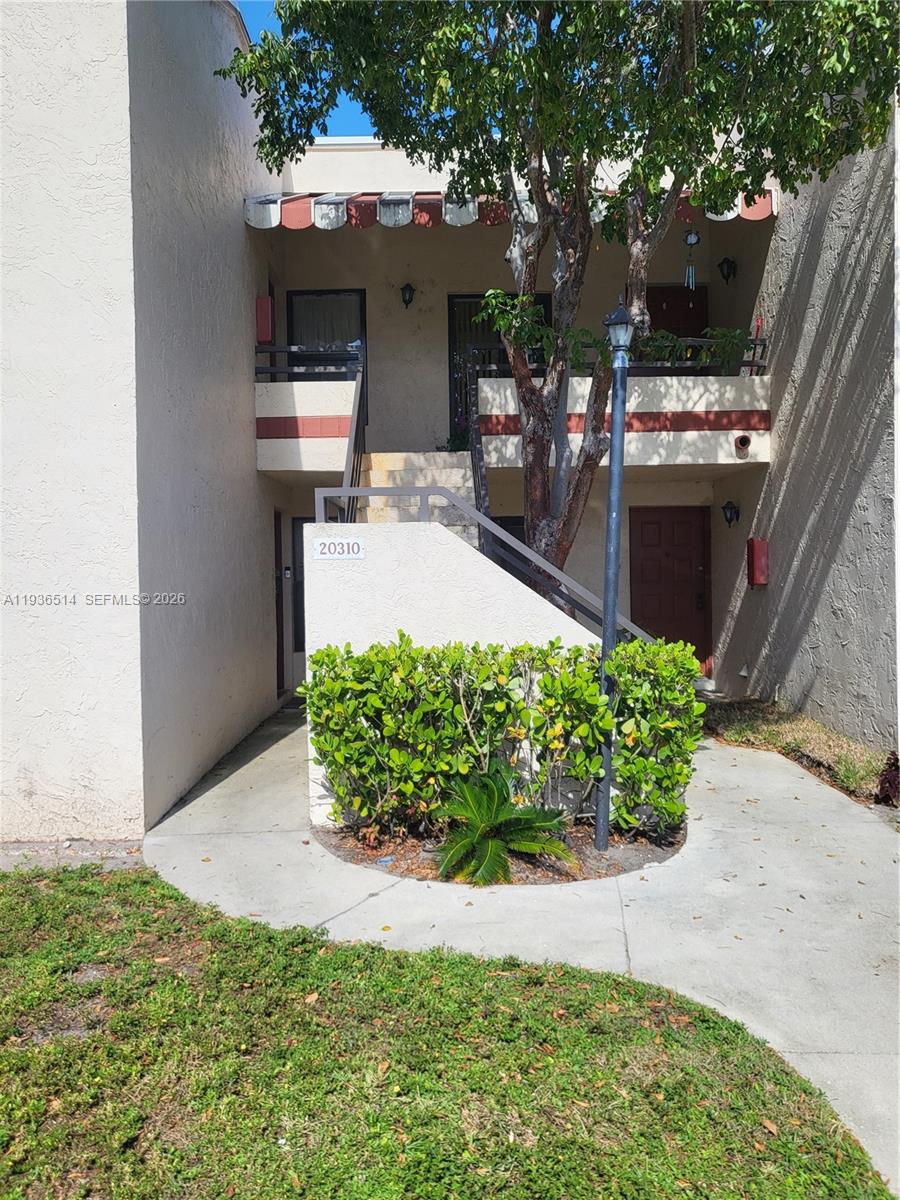 A two-story exterior view shows a staircase leading to an upper-level balcony and entrance — 20310 NE 3rd Ct # 2, Miami FL 33179, MIAMI, FL