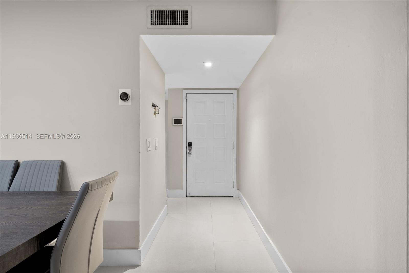 A white front door sits at the end of a tiled hallway with light-colored walls — 20310 NE 3rd Ct # 2, Miami FL 33179, MIAMI, FL