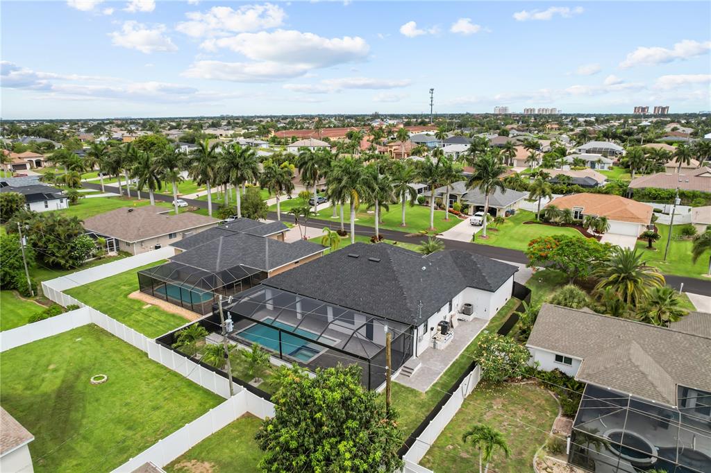 An aerial view shows a residential neighborhood with houses featuring screened-in pools and palm trees — 1709 SW 43RD LANE, CAPE CORAL, FL