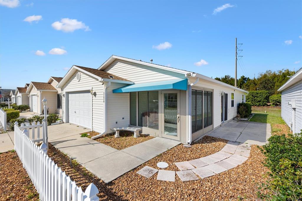 A light-colored house with a garage, a screened-in porch, and a white picket fence — 17470 SE 93RD VINE AVENUE, THE VILLAGES, FL