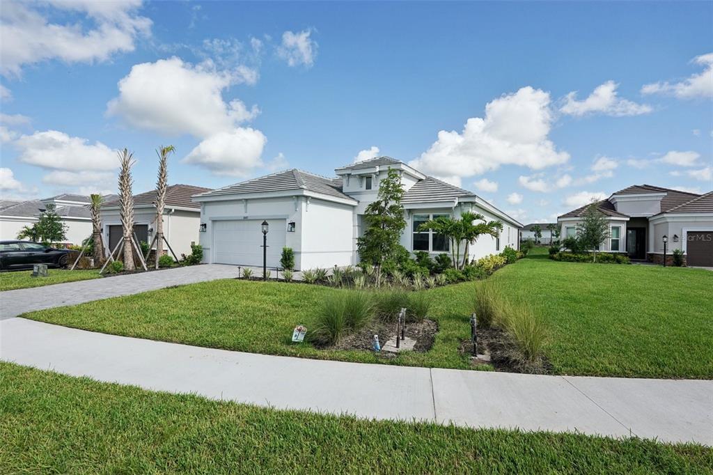 A single-story white house with a two-car garage and a landscaped front lawn — 16415 ISOLA PLACE, LAKEWOOD RANCH, FL
