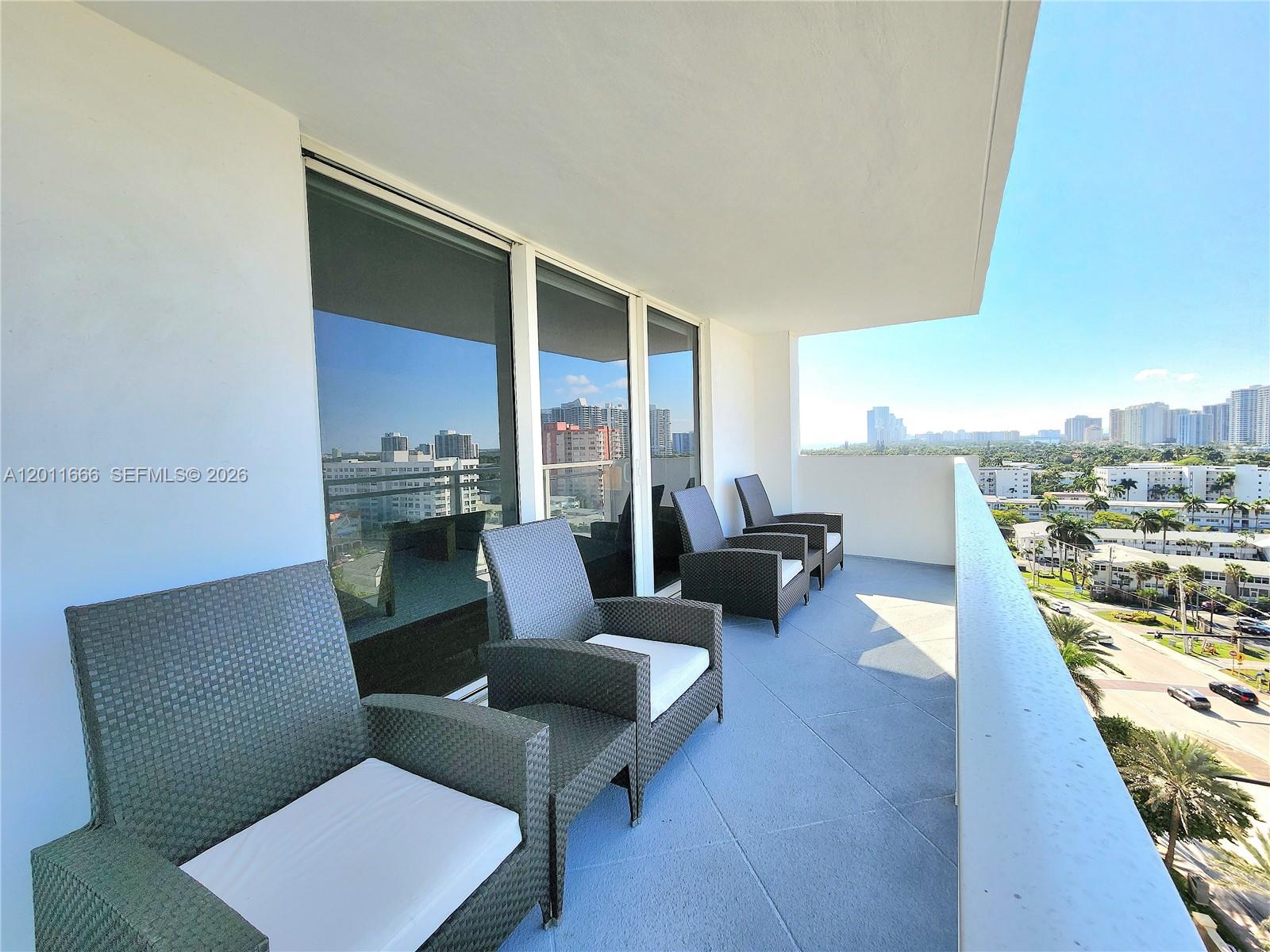A balcony with wicker chairs overlooks a city skyline and a street below — 2030 S Ocean Dr # 1107, Hallandale Beach FL 33009, HALLANDALE BEACH, FL