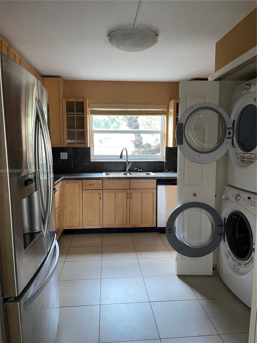 A kitchen features light wood cabinets, stainless steel appliances, and a stacked laundry unit — 7175 Nova Dr # 507, Davie FL 33317, DAVIE, FL