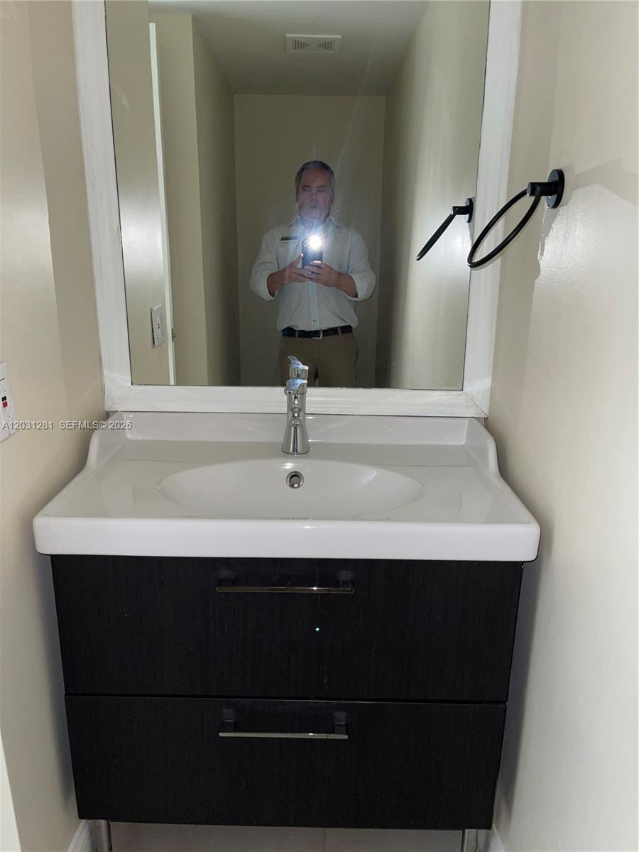 A bathroom vanity with a dark wood cabinet, white sink, and mirror is shown — 7175 Nova Dr # 507, Davie FL 33317, DAVIE, FL