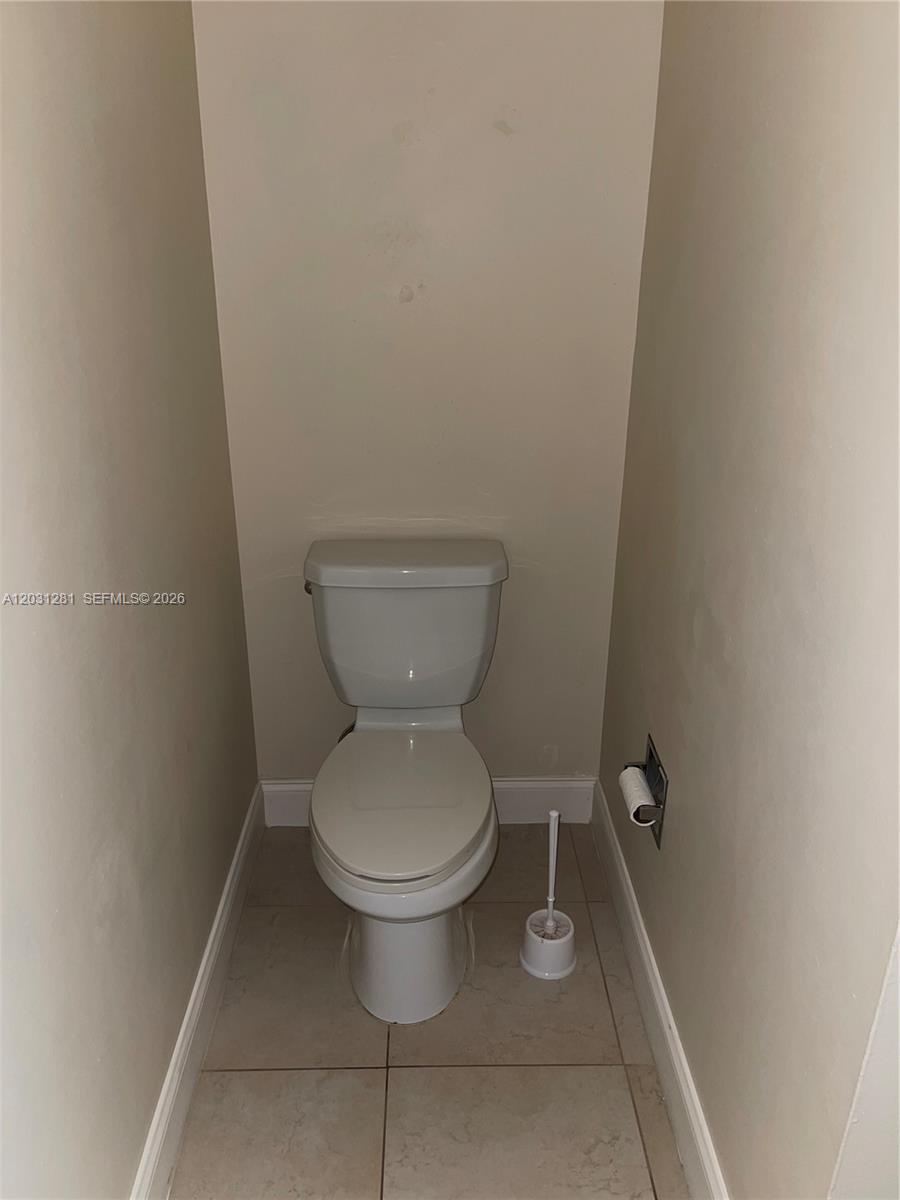 A white toilet is centered in a small, beige-walled bathroom with tiled flooring — 7175 Nova Dr # 507, Davie FL 33317, DAVIE, FL