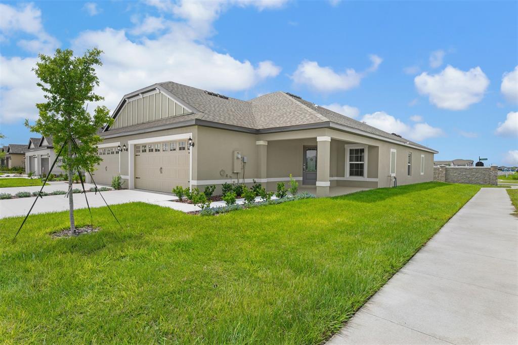 A single-story house with a tan stucco exterior, a two-car garage, and a front lawn — 3176 SEVILLE STREET, LAKE ALFRED, FL