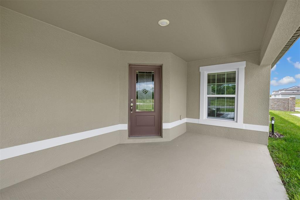A covered concrete porch features a brown front door and a single window — 3176 SEVILLE STREET, LAKE ALFRED, FL
