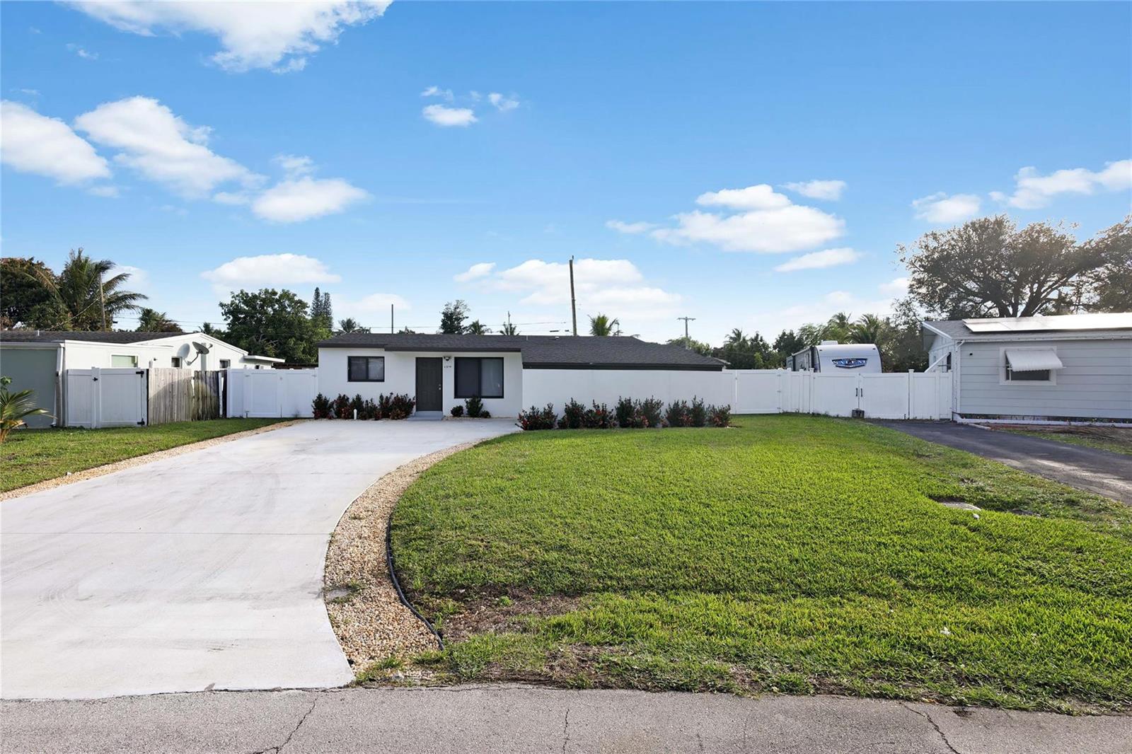 A single-story house with a white exterior, a curved concrete driveway, and a large front lawn — 6374 SW 2nd Street, Margate FL 33068, MARGATE, FL