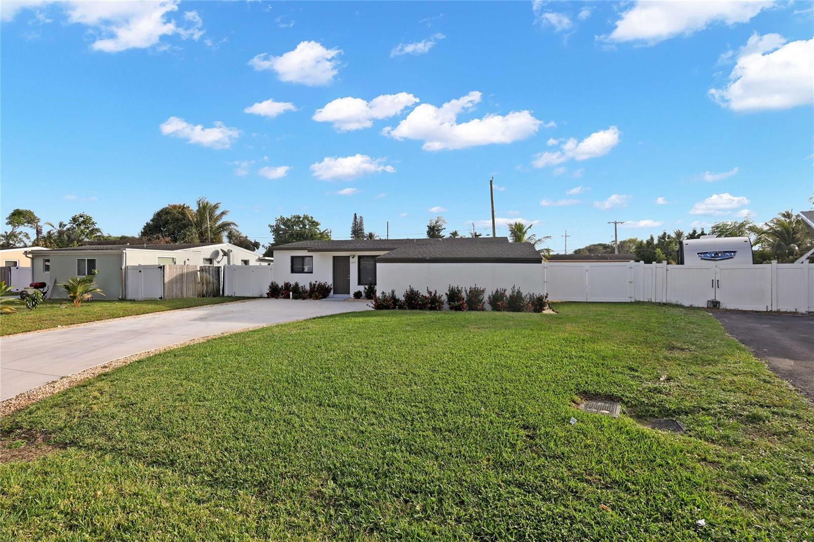 A single-story house with a white exterior, a concrete driveway, and a large front lawn — 6374 SW 2nd Street, Margate FL 33068, MARGATE, FL