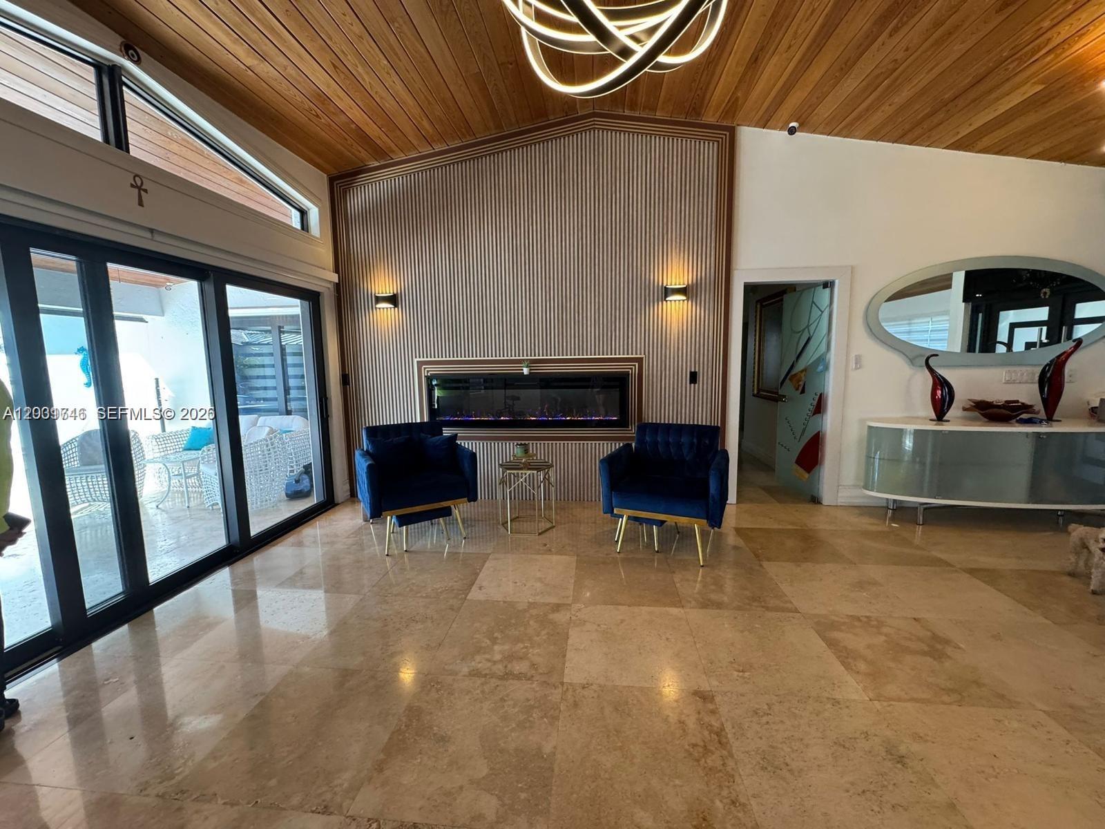 A living room features a fireplace, blue armchairs, a wood-paneled ceiling, and large glass doors — 3690 SW 139th Ave, Miami FL 33175, MIAMI, FL