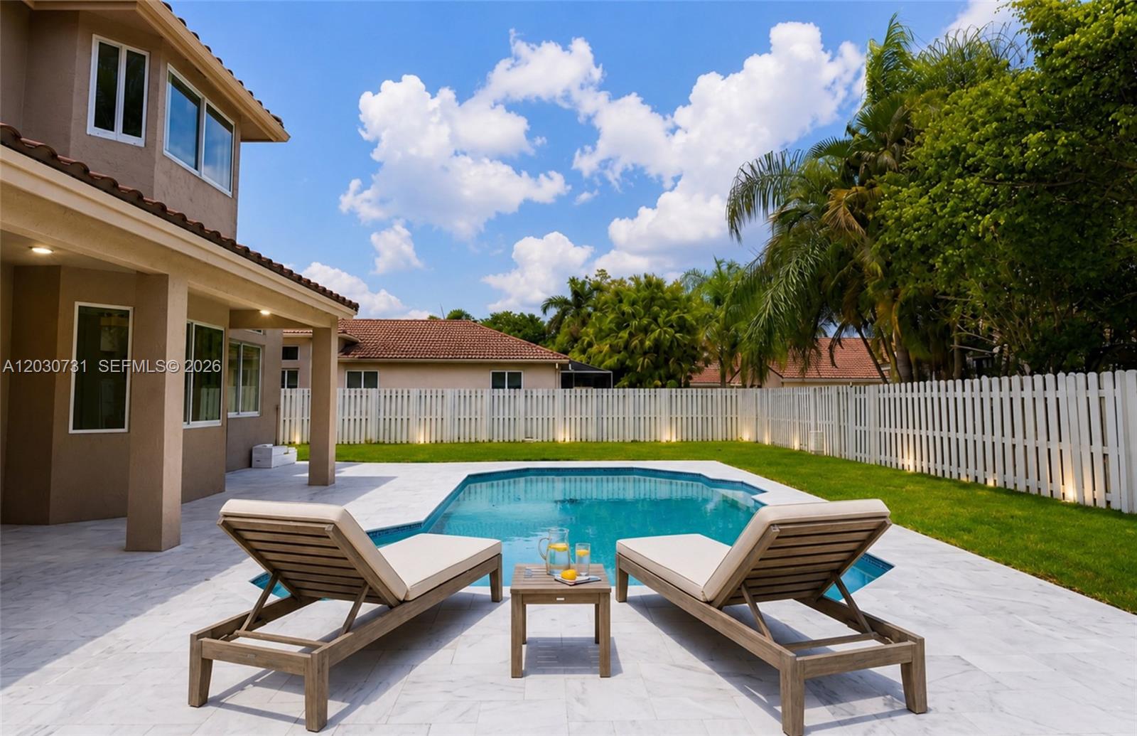 A backyard features a swimming pool, two lounge chairs, and a white fence — 852 Heritage Dr, Weston FL 33326, WESTON, FL