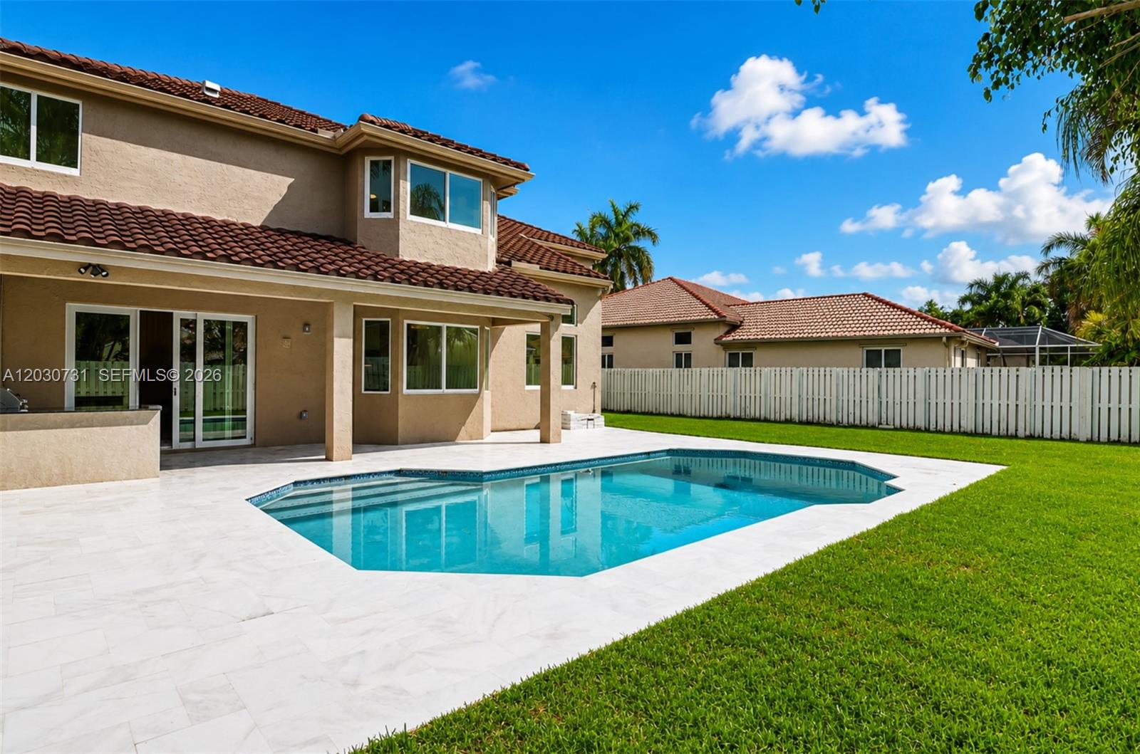 A two-story house with a backyard swimming pool, patio, and white fence under blue sky — 852 Heritage Dr, Weston FL 33326, WESTON, FL