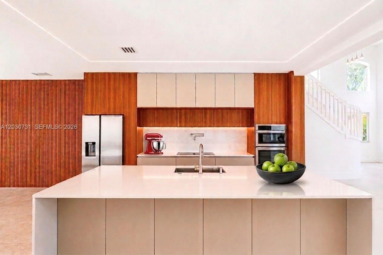 A modern kitchen features a large white island, light cabinetry, and warm wood paneling — 852 Heritage Dr, Weston FL 33326, WESTON, FL