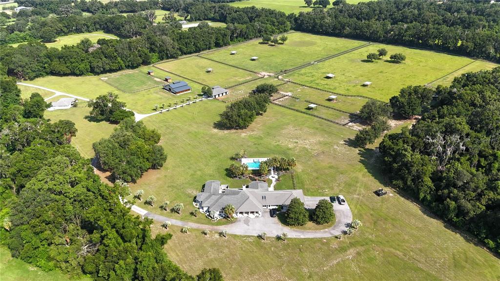 An aerial view shows a large house with a pool surrounded by fenced pastures and trees — 14285 N US HIGHWAY 441, CITRA, FL