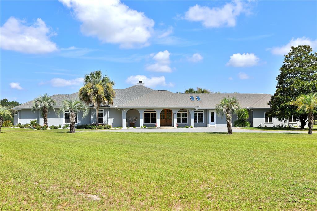 A single-story gray house with a covered entryway and palm trees on a grassy lawn — 14285 N US HIGHWAY 441, CITRA, FL