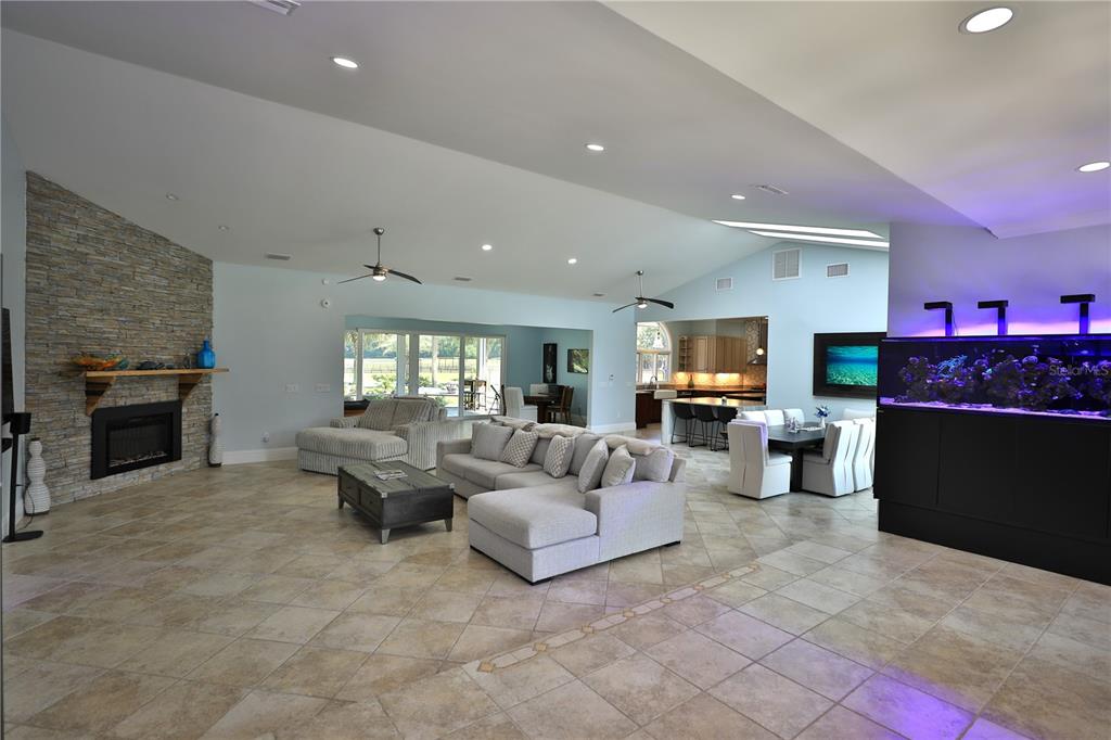 An open-concept living area features a stone fireplace, a large sectional sofa, and a kitchen — 14285 N US HIGHWAY 441, CITRA, FL