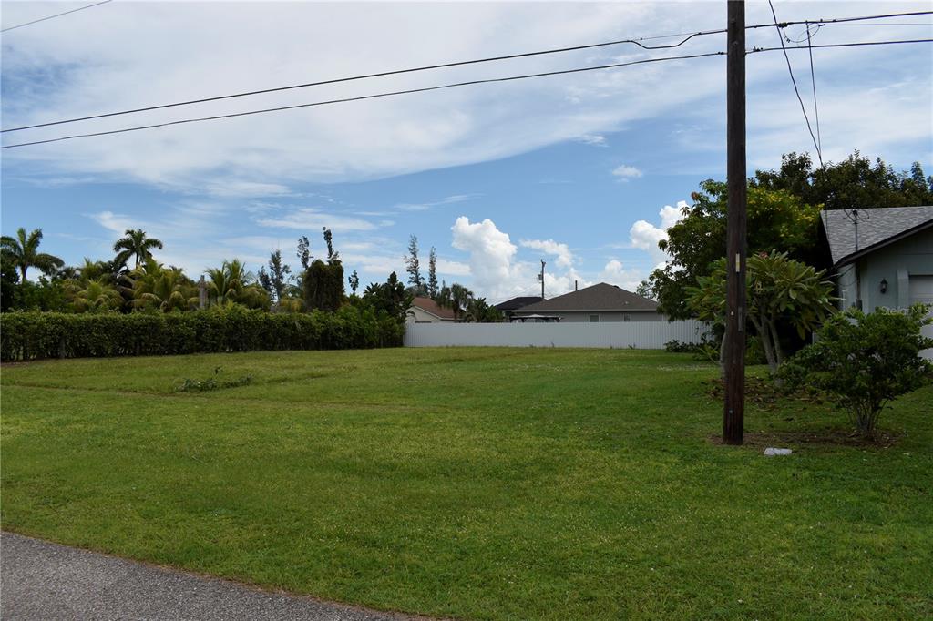 A grassy, vacant residential lot is bordered by a white fence and mature trees — 805 SW 6TH COURT, CAPE CORAL, FL