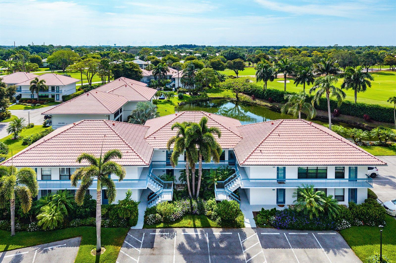 An aerial view of a two-story apartment building with a tiled roof and palm trees — 4080-b Quail Ridge Drive, Boynton Beach FL 33436, BOYNTON BEACH, FL