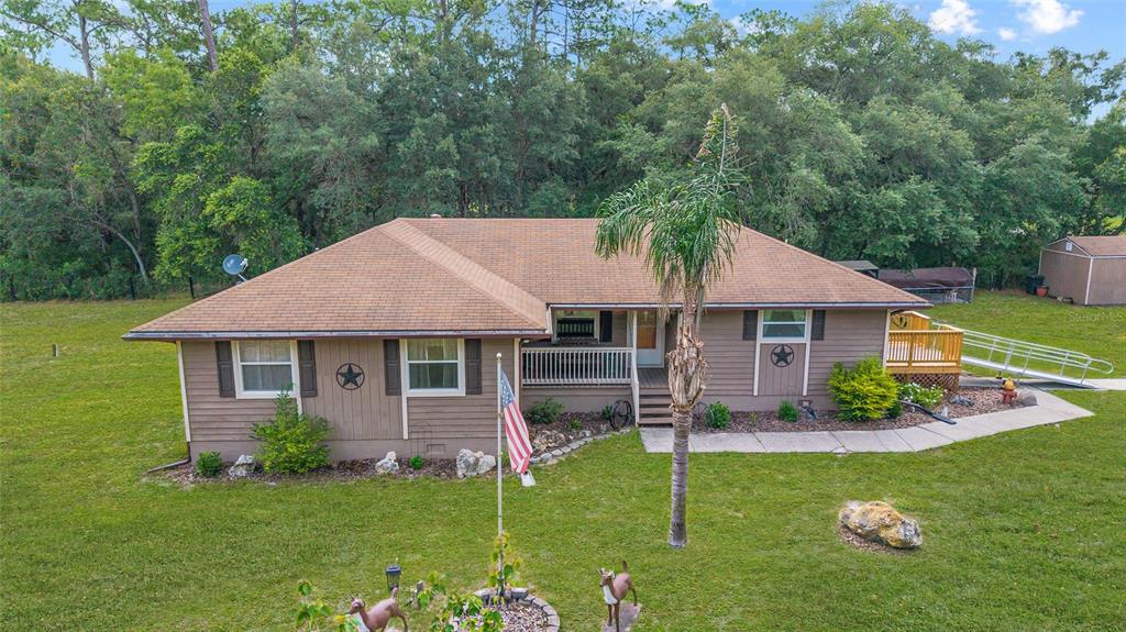 A single-story house with brown siding, a shingled roof, a front porch, and a flagpole — 15755 SW 90TH AVENUE, DUNNELLON, FL