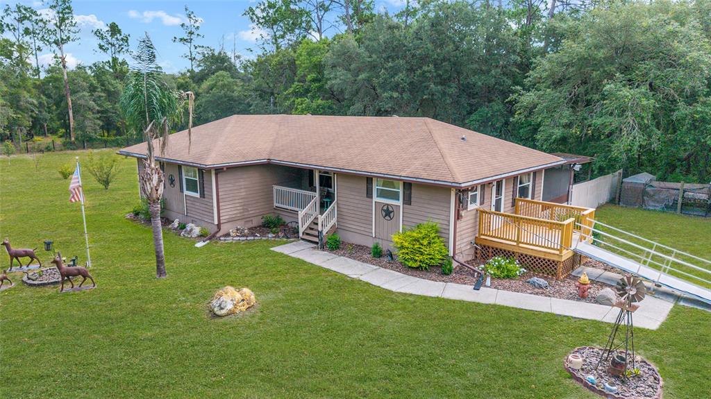 An exterior view of a single-story house with a wooden deck and wheelchair ramp — 15755 SW 90TH AVENUE, DUNNELLON, FL
