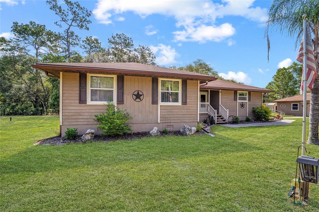 A single-story house with tan siding, brown shutters, and a metal star wall decoration — 15755 SW 90TH AVENUE, DUNNELLON, FL