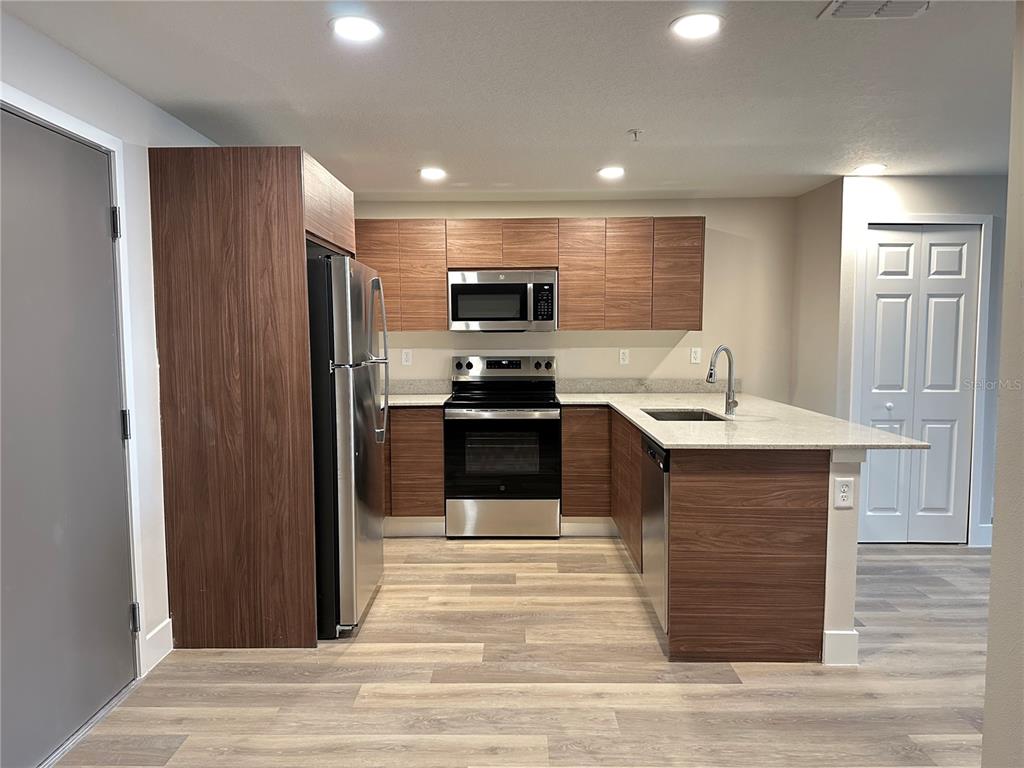 A kitchen features wood-grain cabinets, stainless steel appliances, and a peninsula with a sink — 4424 S TEXAS AVENUE UNIT 110, ORLANDO, FL