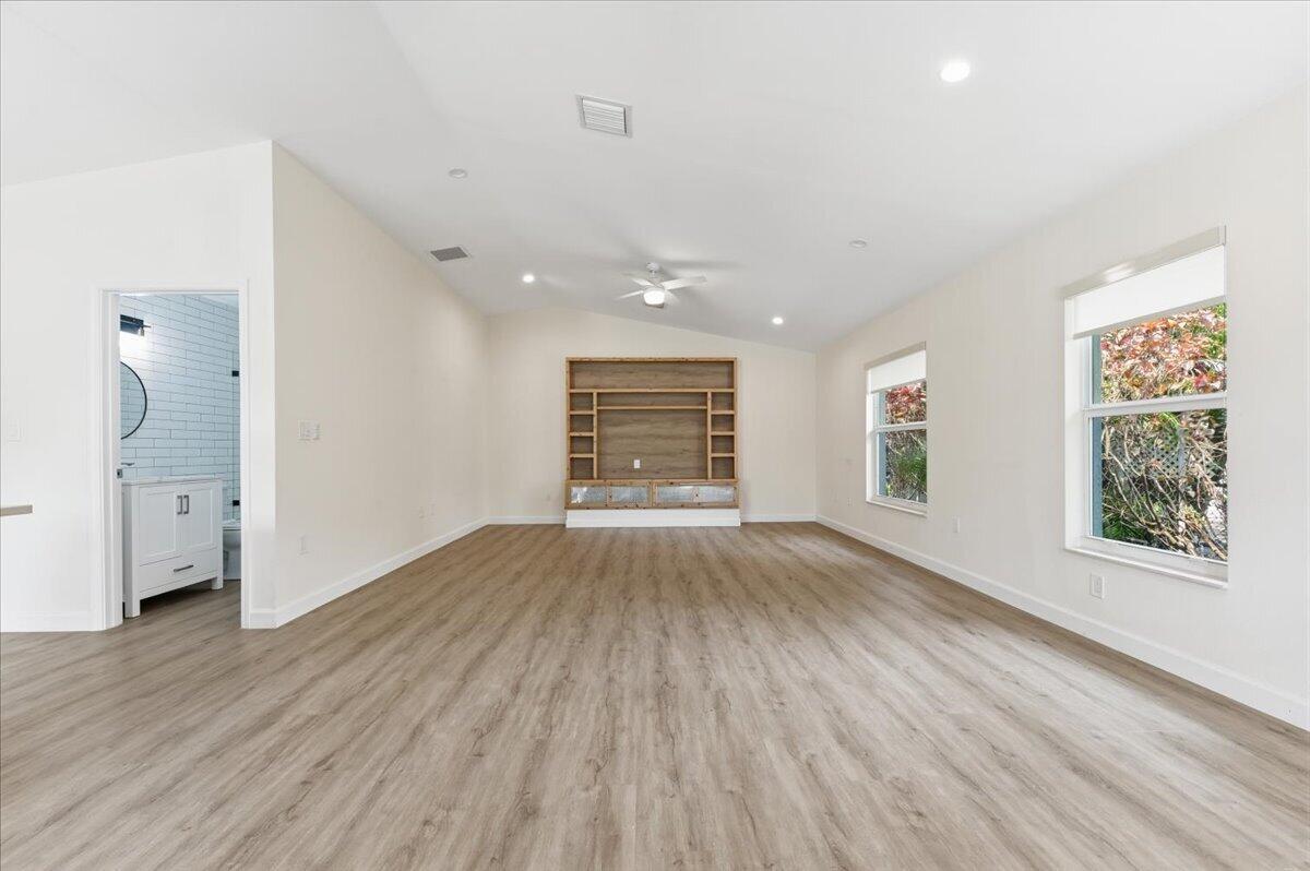 A spacious room with light wood-look flooring, white walls, and a built-in wooden media center — 530 NE 3rd Avenue NE, Delray Beach FL 33444, DELRAY BEACH, FL
