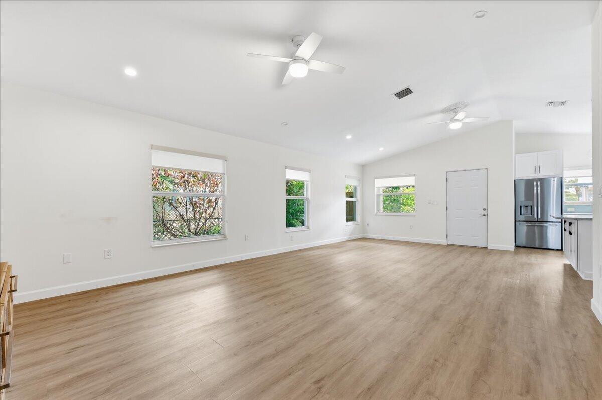 An open-concept living area features light wood-look flooring, white walls, and a ceiling fan — 530 NE 3rd Avenue NE, Delray Beach FL 33444, DELRAY BEACH, FL