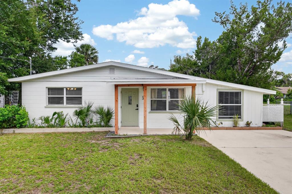 A single-story white house with a green front door and a small covered porch — 94 ROGERS PARK DRIVE, ORMOND BEACH, FL
