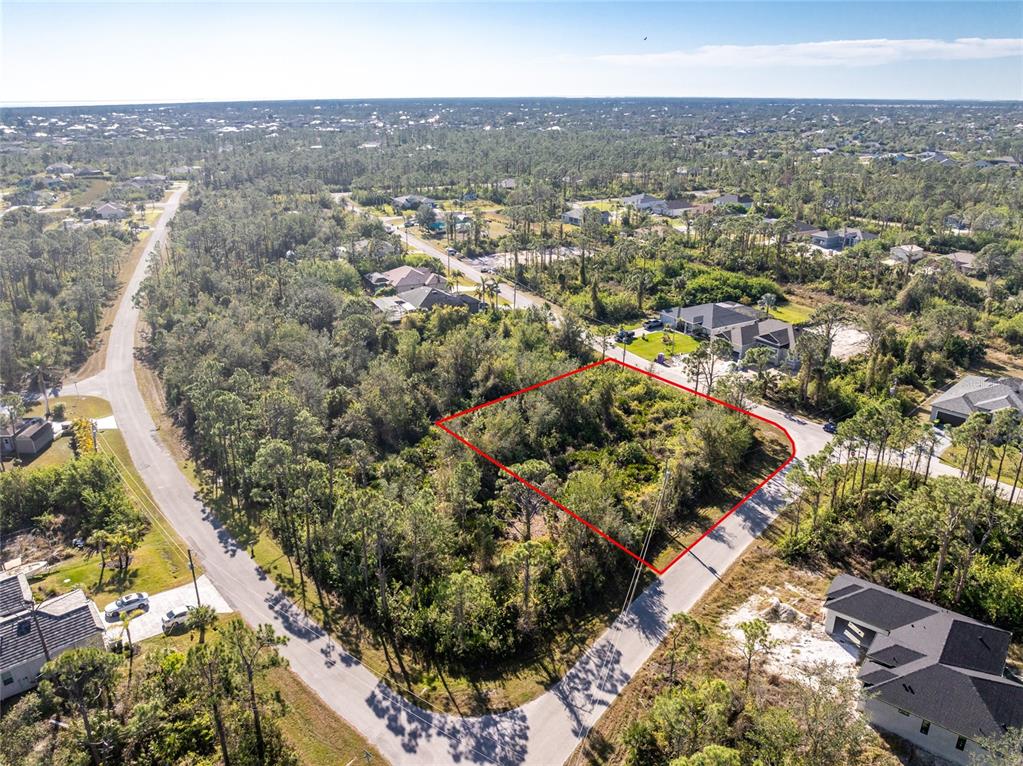 An aerial view shows a vacant, wooded residential lot outlined in red between two roads — 8281 CONSUL STREET, PORT CHARLOTTE, FL